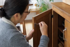 家具扉のマグネットキャッチを確認する50代女性